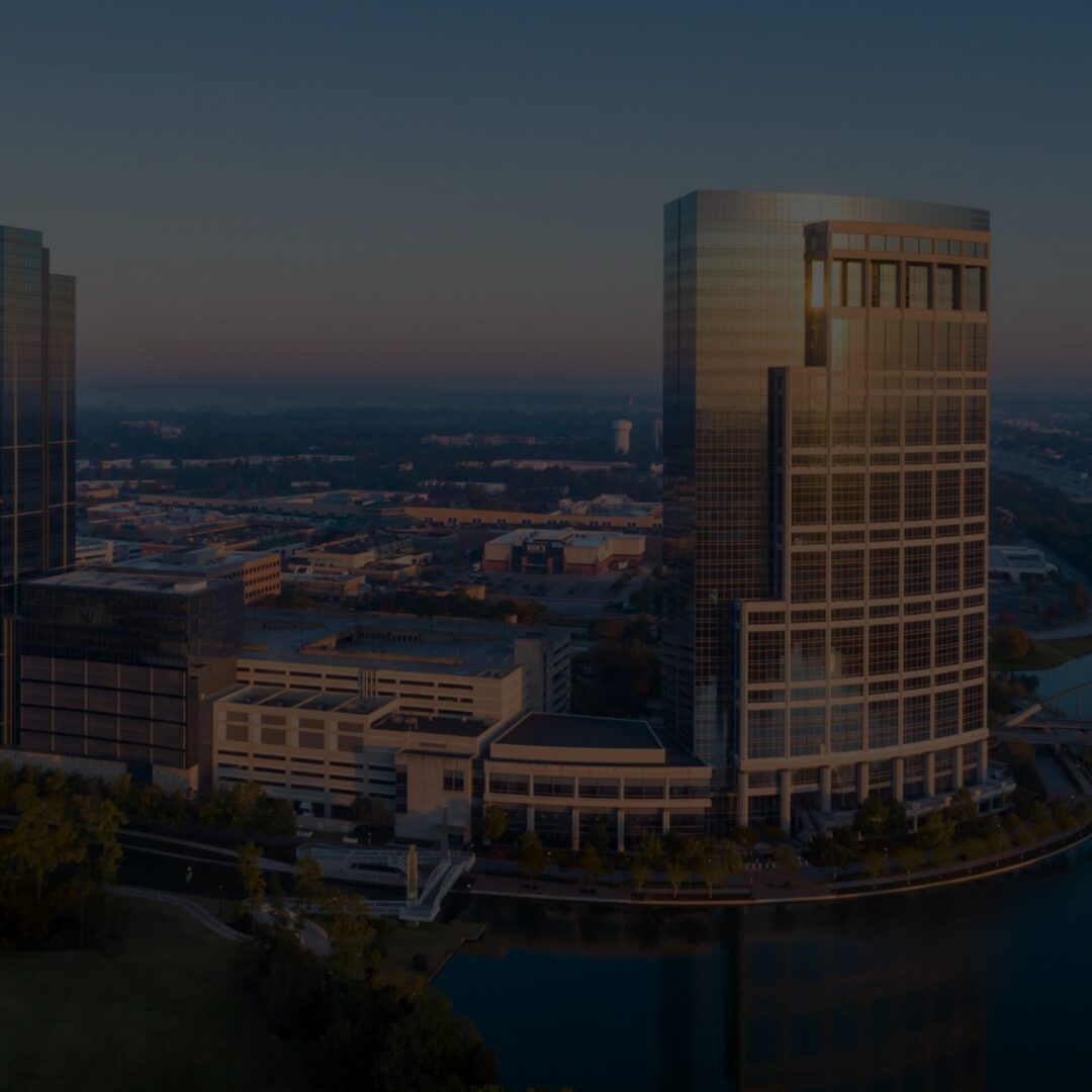 Modern skyscraper reflecting sunset over a cityscape.